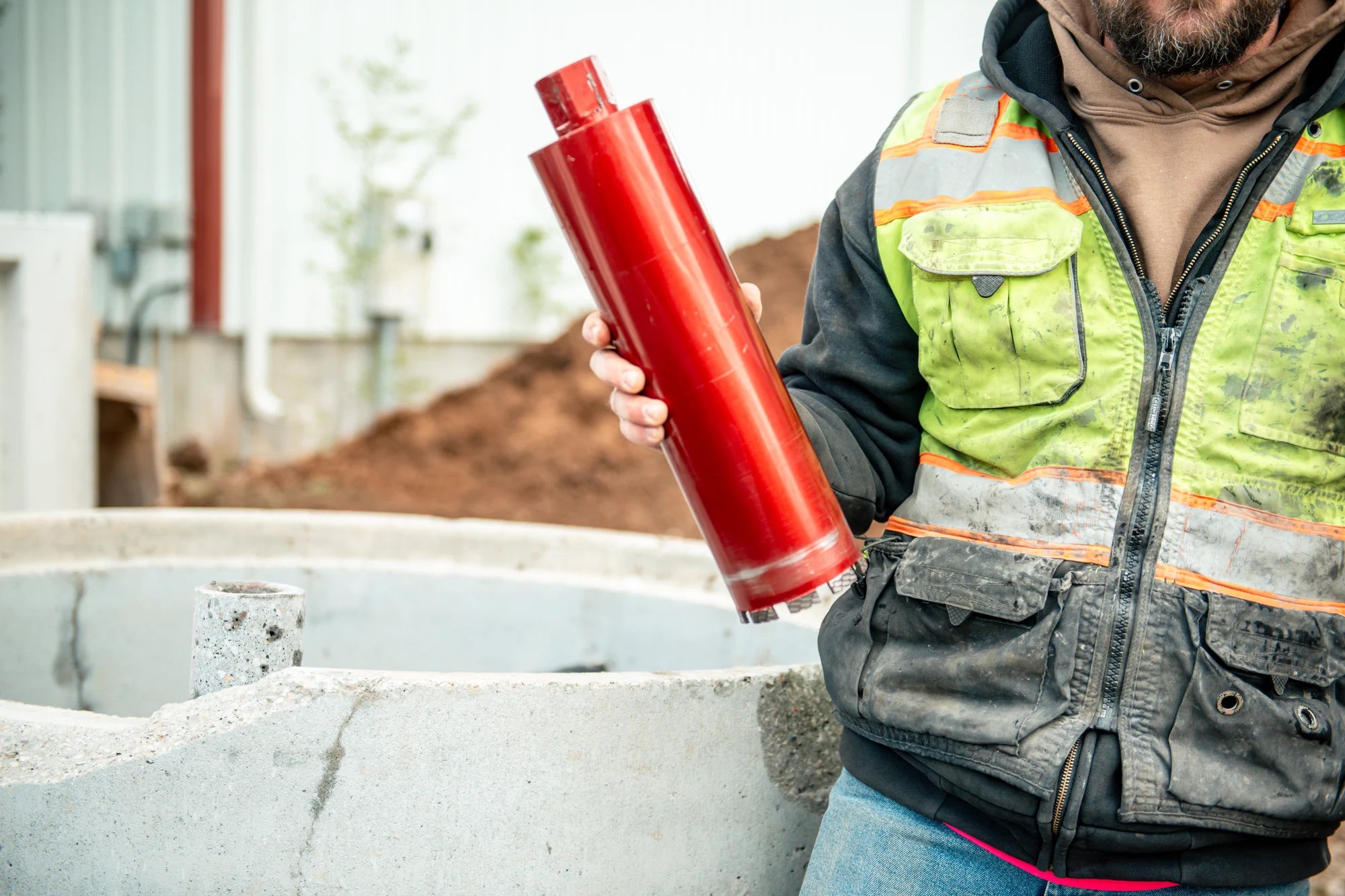 Contractor holding a red diamond core bit on a jobsite